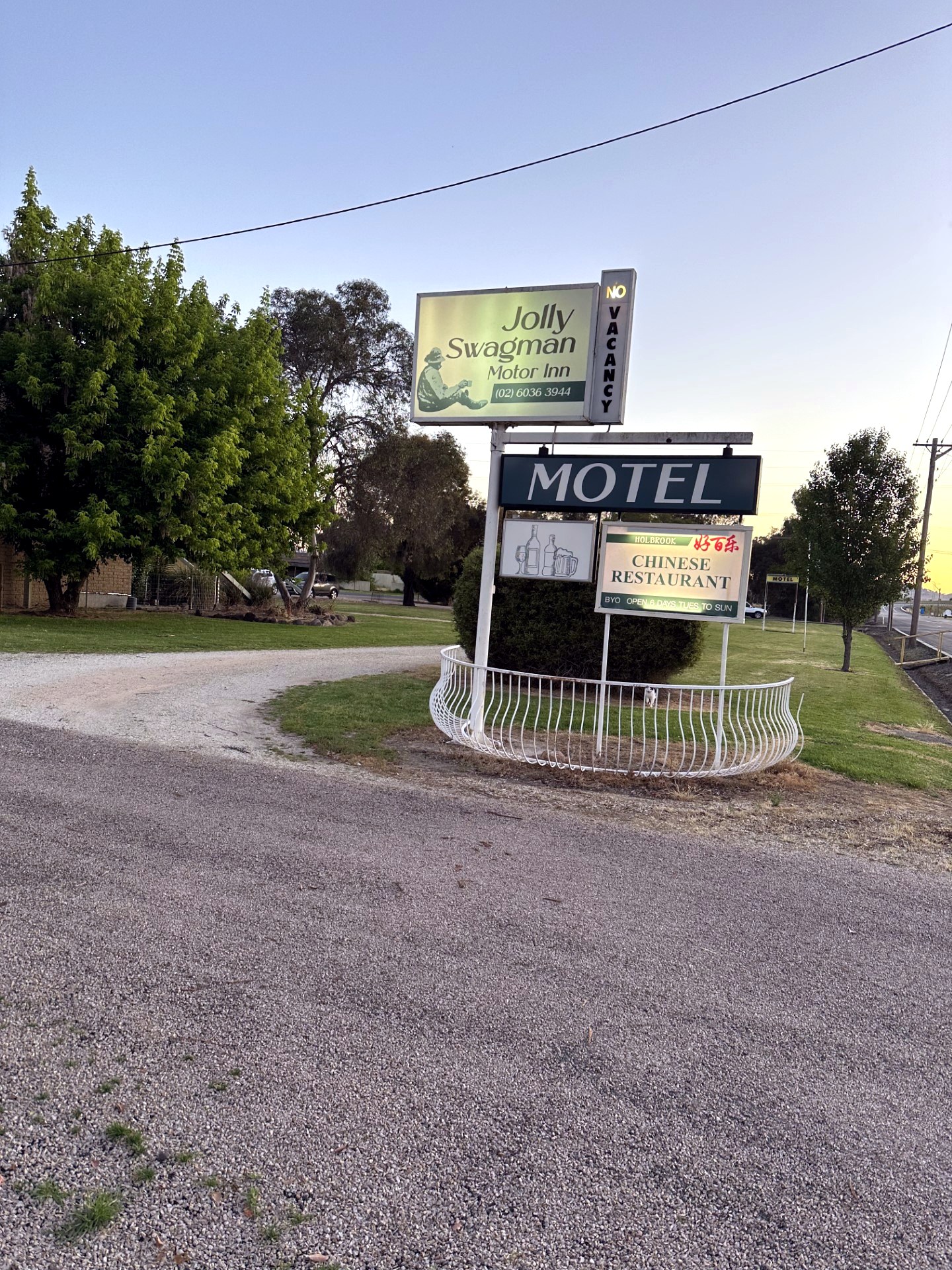 The Jolly Swagman Motor Inn sign glowing at dusk on Albury Street, Holbrook